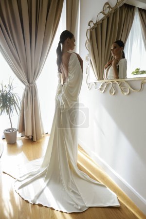 Téléchargez les photos : Photo de mode de belle mariée dans la robe de mariée élégante et accessoires posant dans la chambre d'hôtel élégante - en image libre de droit