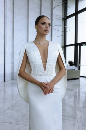 Téléchargez les photos : Photo de mode de belle mariée dans la robe de mariée élégante et accessoires posant dans la chambre d'hôtel élégante - en image libre de droit