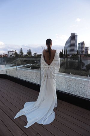 Foto de Foto de moda de la novia hermosa en vestido de novia elegante y accesorios posando al aire libre - Imagen libre de derechos