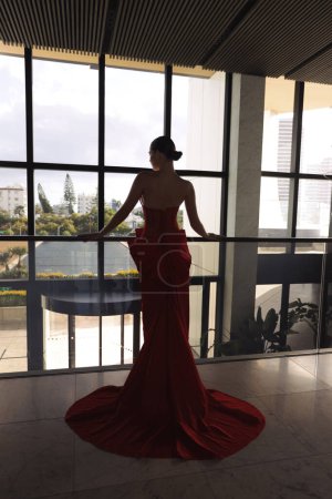 Photo for Fashion photo of beautiful woman with dark hair in elegant red dress with accessories posing in luxurious hotel lobby - Royalty Free Image