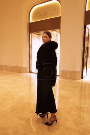 Photo for Fashion interior photo of beautiful sensual woman with dark hair in luxurious black fur coat and jewelry posing in hall of the hotel - Royalty Free Image
