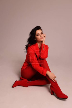 Photo for Fashion photo of beautiful woman with dark hair in luxurious red suit posing in the studio - Royalty Free Image