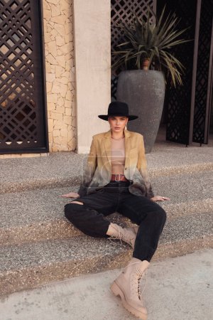Téléchargez les photos : Photo de mode en plein air de belle femme slave aux cheveux foncés en vêtements décontractés et chapeau noir posant dans la rue de Limassol - en image libre de droit