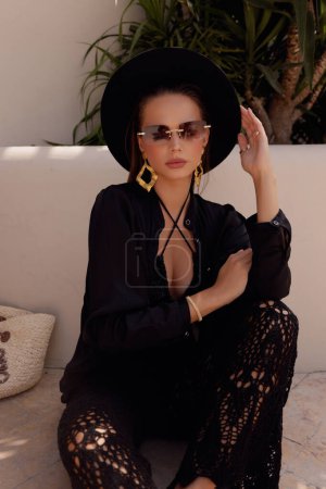 Photo for Fashion photo of beautiful woman with dark hair in elegant clothes with accessories posing in summer beach club - Royalty Free Image