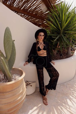 Foto de Foto de moda de una hermosa mujer con cabello oscuro en ropa elegante con accesorios posando en el club de playa de verano - Imagen libre de derechos