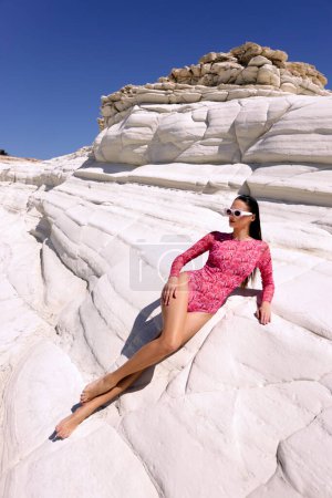 Photo for Fashion outdoor photo of beautiful sensual woman with dark hair in elegant printed beach clothes posing in the white rock beach on Cyprus - Royalty Free Image
