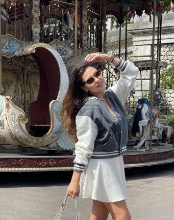 Téléchargez les photos : Photo extérieure de mode de belle femme aux cheveux foncés en vêtements décontractés posant sur Montmartre près du carrousel - en image libre de droit