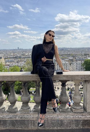 Téléchargez les photos : Photo extérieure de mode de belle femme aux cheveux foncés dans des vêtements classiques élégants posant sur Montmartre avec une vue panoramique sur Paris - en image libre de droit