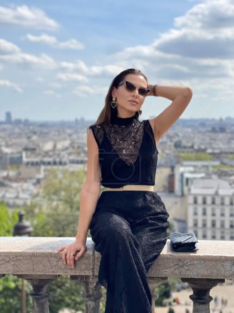 Photo for Fashion outdoor photo of beautiful woman with dark hair in elegant classic clothes posing on Montmartre with a panoramic view of Paris - Royalty Free Image