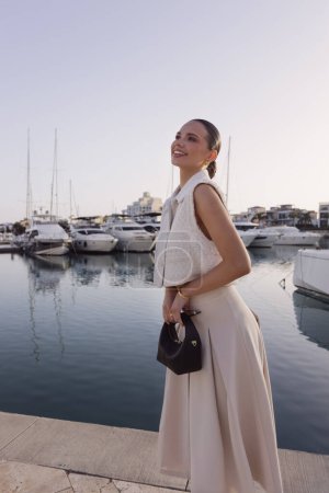Photo for Fashion outdoor photos of beautiful woman with dark hair in elegant classic clothes with accessories posing at the marina with the yachts in Cyprus - Royalty Free Image