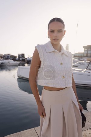 Photo for Fashion outdoor photos of beautiful woman with dark hair in elegant classic clothes with accessories posing at the marina with the yachts in Cyprus - Royalty Free Image