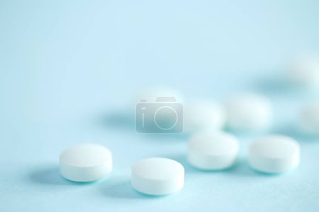 Téléchargez les photos : Pilules médicales blanches sur fond bleu - en image libre de droit