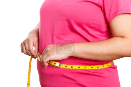 Téléchargez les photos : Grosse femme mesurant son estomac isolé sur fond blanc. Surpoids, obésité. Concept de mode de vie alimentation femme - en image libre de droit