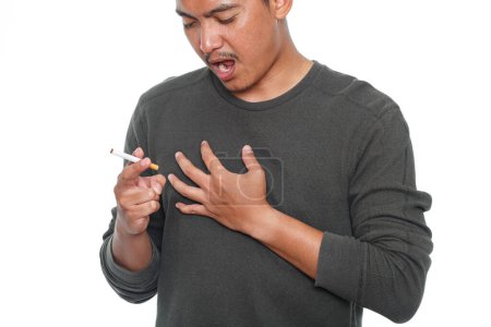 Foto de Hombre fumando un cigarrillo y sintiendo dolor en el pecho. Enfermedades del corazón o el concepto pulmonar - Imagen libre de derechos