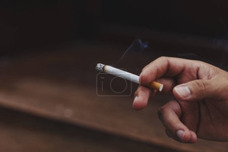 Photo for Man holding smoking a cigarette in hand - Royalty Free Image