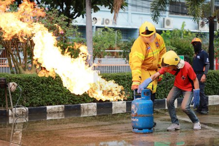 Téléchargez les photos : Nakhon Ratchasima, Thaïlande - 1 Juillet 2023 : Tutoriel comment donner la sécurité incendie, éteindre le feu. Formation des employés à la lutte contre l'incendie, Éteignez le robinet du réservoir de gaz qui s'allume. - en image libre de droit