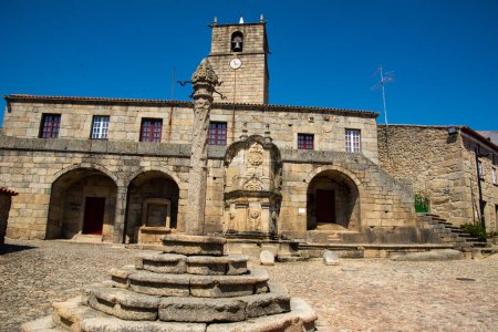 Foto de Vista del antiguo ayuntamiento de Castelo Novo, Portugal. También se puede ver el pelourinho en primer plano y la torre del castillo en el fondo. - Imagen libre de derechos