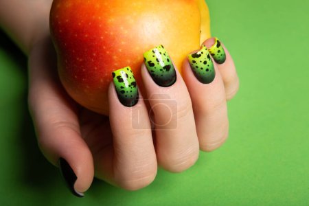 Photo for Female neat hand with short natural nails painted with green nail polish holding apple. Natural, cozy, elegant, modern look. High-quality photo - Royalty Free Image