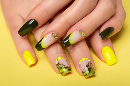 Foto de Female hands with black and yellow nail design. Yellow nail polish manicured hands. Female hands on yellow background. High quality photo - Imagen libre de derechos
