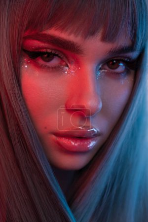 Photo for High fashion model face woman in colorful bright neon UV blue and red lights, posing in studio, beautiful girl, glowing makeup, colorful makeup. Glitter Bright Neon Makeup. High quality photo - Royalty Free Image