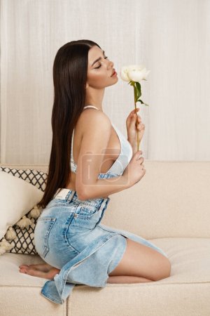 Photo for Beautiful young woman sitting in a trendy denim suit on sofa, indoors. High quality photo - Royalty Free Image