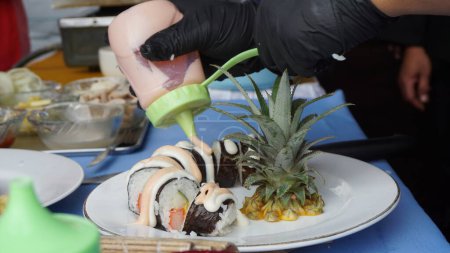 Foto de Chef preparando comida japonesa. Chef japonés haciendo sushi para los clientes. Joven chef que sirve sushi tradicional japonés con piña - Imagen libre de derechos