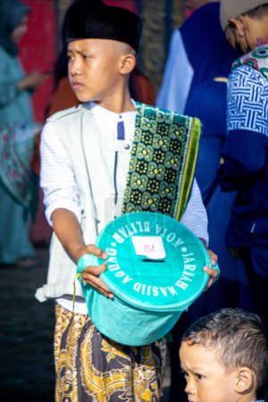 Téléchargez les photos : Les Indonésiens recueillent des fonds auprès de la communauté lorsqu'ils prient l'Aïd al-Fitr à la mosquée - en image libre de droit