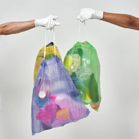 Photo for Partial multiracial couple volunteers hands hold sorted garbage bags. Volunteering. Ecology safety. Waste disposal and recycling. Environmental sustainability. Isolated on white background in studio - Royalty Free Image