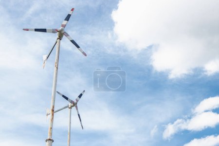 Photo for The side of a rusty metal stand of windwheels is spin in the blue sky. - Royalty Free Image