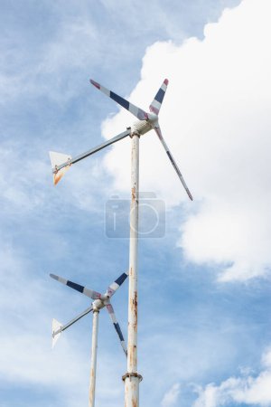 Photo for The side of a rusty metal stand of windwheels is spin in the blue sky. - Royalty Free Image