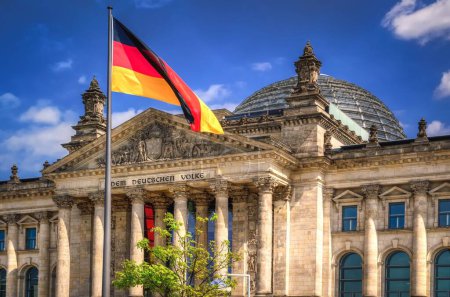 The Reichstag building in Berlin City. Flag of the Federal Republic of Germany is waving in front of the national german parliament.