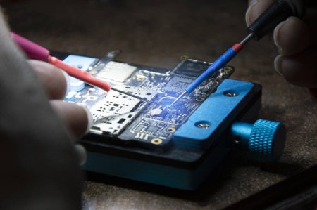 Foto de Vista lateral de mecánico haciendo reparaciones placa base Smartphone, reparación de teléfonos inteligentes, reparación de circuitos - Imagen libre de derechos