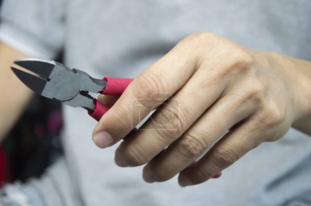 Mechanic holds red handle cutting pliers, mechanic's tools