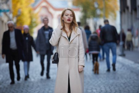 Foto de Mujer de moda en abrigo con labios rojos posando en la calle - Imagen libre de derechos