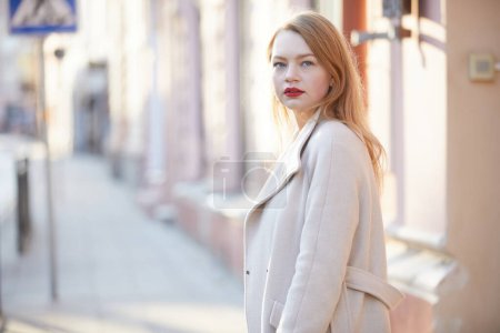 Téléchargez les photos : Femme de mode en manteau avec des lèvres rouges posant dans la rue - en image libre de droit