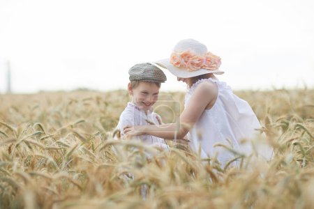 Foto de Retrato de niño y niña felices en sombreros de pie en el campo de trigo - Imagen libre de derechos