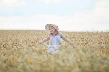Foto de Retrato de niña feliz en sombrero de pie en el campo de trigo - Imagen libre de derechos