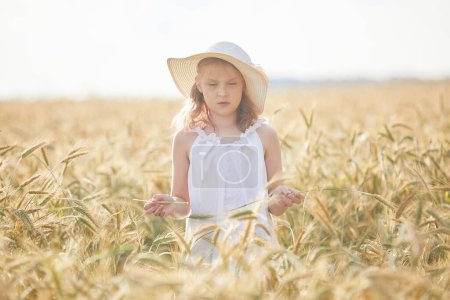 Téléchargez les photos : Portrait de fille heureuse en chapeau debout dans le champ de blé - en image libre de droit