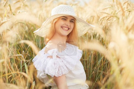 Téléchargez les photos : Portrait de jeune femme en chapeau posant à la caméra dans le champ de blé - en image libre de droit