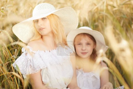 Téléchargez les photos : Mère avec sa fille regardant la caméra dans le champ de blé - en image libre de droit