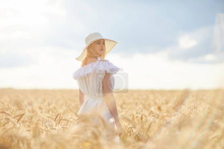 Téléchargez les photos : Femme caucasienne en chapeau, posant dans le champ de blé pendant la journée - en image libre de droit