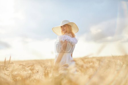 Téléchargez les photos : Femme caucasienne en chapeau posant dans le champ de blé pendant la journée - en image libre de droit