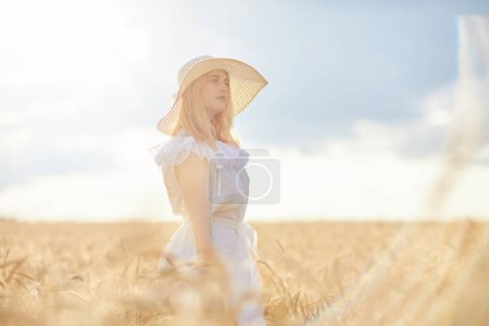 Téléchargez les photos : Femme caucasienne en chapeau posant dans le champ de blé pendant la journée - en image libre de droit