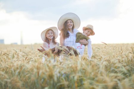 Téléchargez les photos : Mère avec des enfants posant dans le champ de blé - en image libre de droit