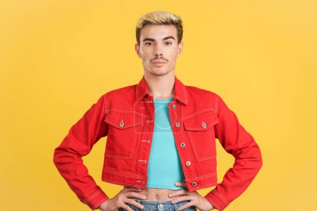 Photo for Gay man in colorful clothes looking at camera in studio with yellow background - Royalty Free Image
