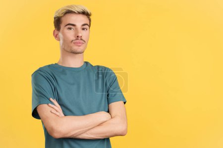 Photo for Relaxed gay man standing whit arms crossed looking at camera in studio with yellow background - Royalty Free Image