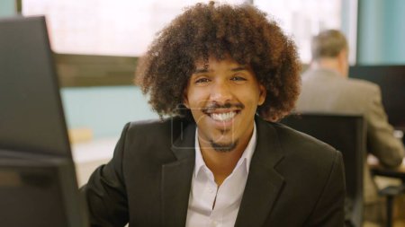 African american man smiling at camera while working in a coworking