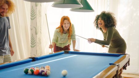 Friends laughing when woman playing awful at pool trying to hit the ball without luck