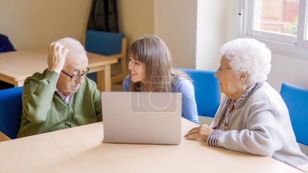 Téléchargez les photos : Petite-fille aidant ses grands-parents à utiliser l'ordinateur portable. Son grand-père a du mal à le comprendre. - en image libre de droit