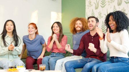 Grupo de amigos celebrando algo que están viendo en la televisión mientras toman una copa en casa